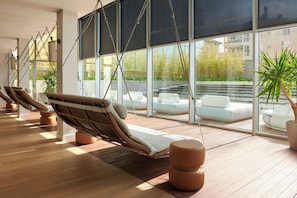 A modern lounge area with wicker lounge chairs and a large window offering a view of the outdoors. - Le Meridien Ra Beach Hotel & Spa (El Vendrell)