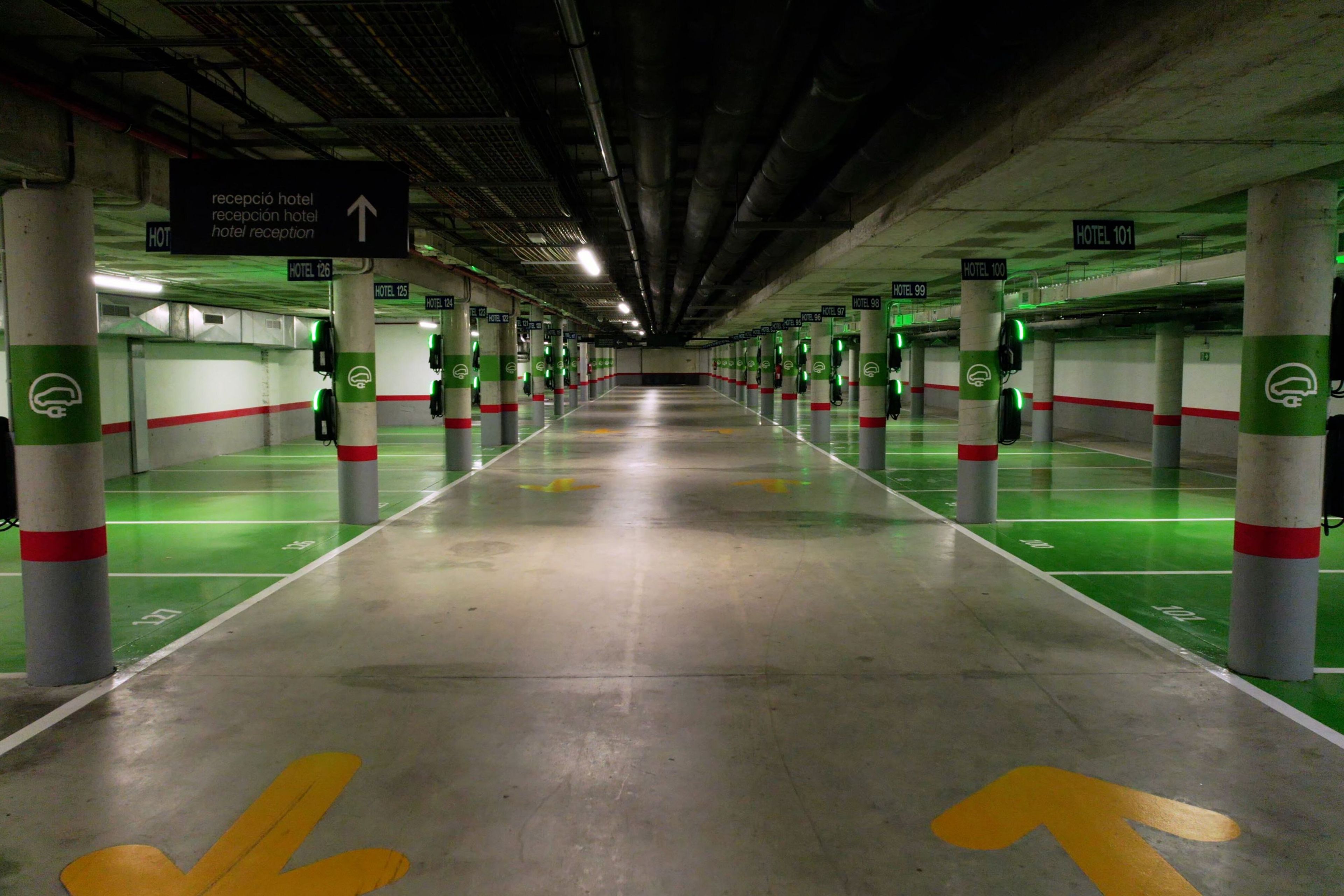 Un estacionamiento de varios niveles con señales direccionales y espacios de estacionamiento verdes.