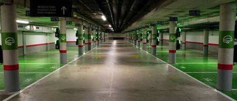 Un estacionamiento de varios niveles con señales direccionales y espacios de estacionamiento verdes.