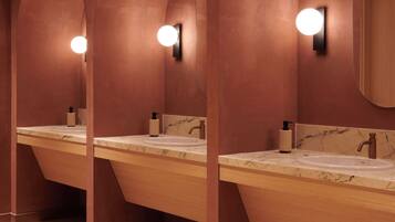 A row of wooden vanity mirrors with built-in lighting, marble countertops, and a tiled floor.