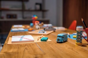 A wooden table with a notebook, a small blue toy bus, a pencil, and a polka-dotted cup. - Le Meridien Ra Beach Hotel & Spa (El Vendrell)