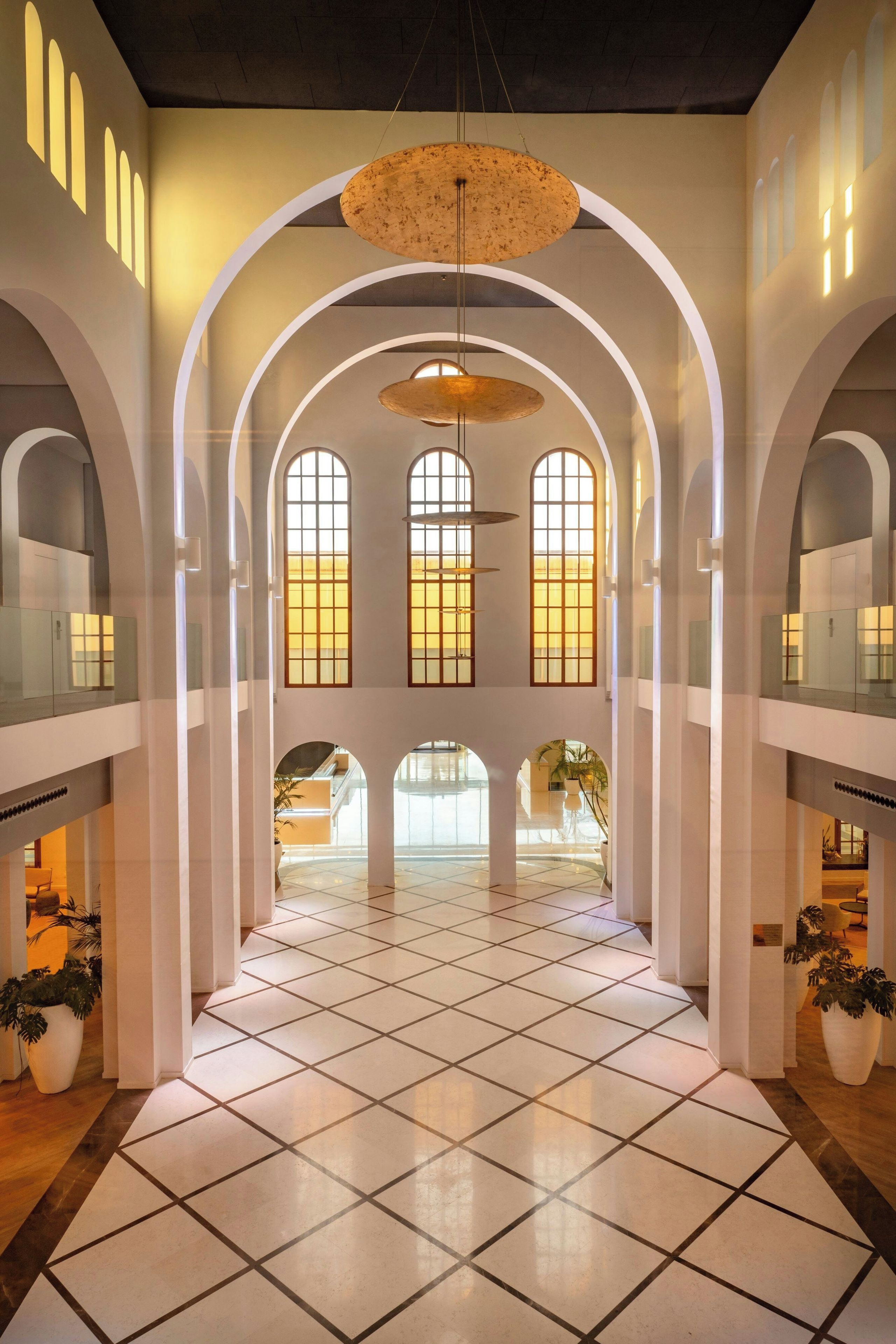 Un intérieur spacieux avec de hauts plafonds, des fenêtres en arc de cercle et un sol carrelé.