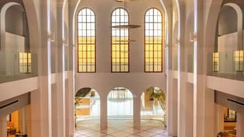 Un intérieur spacieux avec de hauts plafonds, des fenêtres en arc de cercle et un sol carrelé.