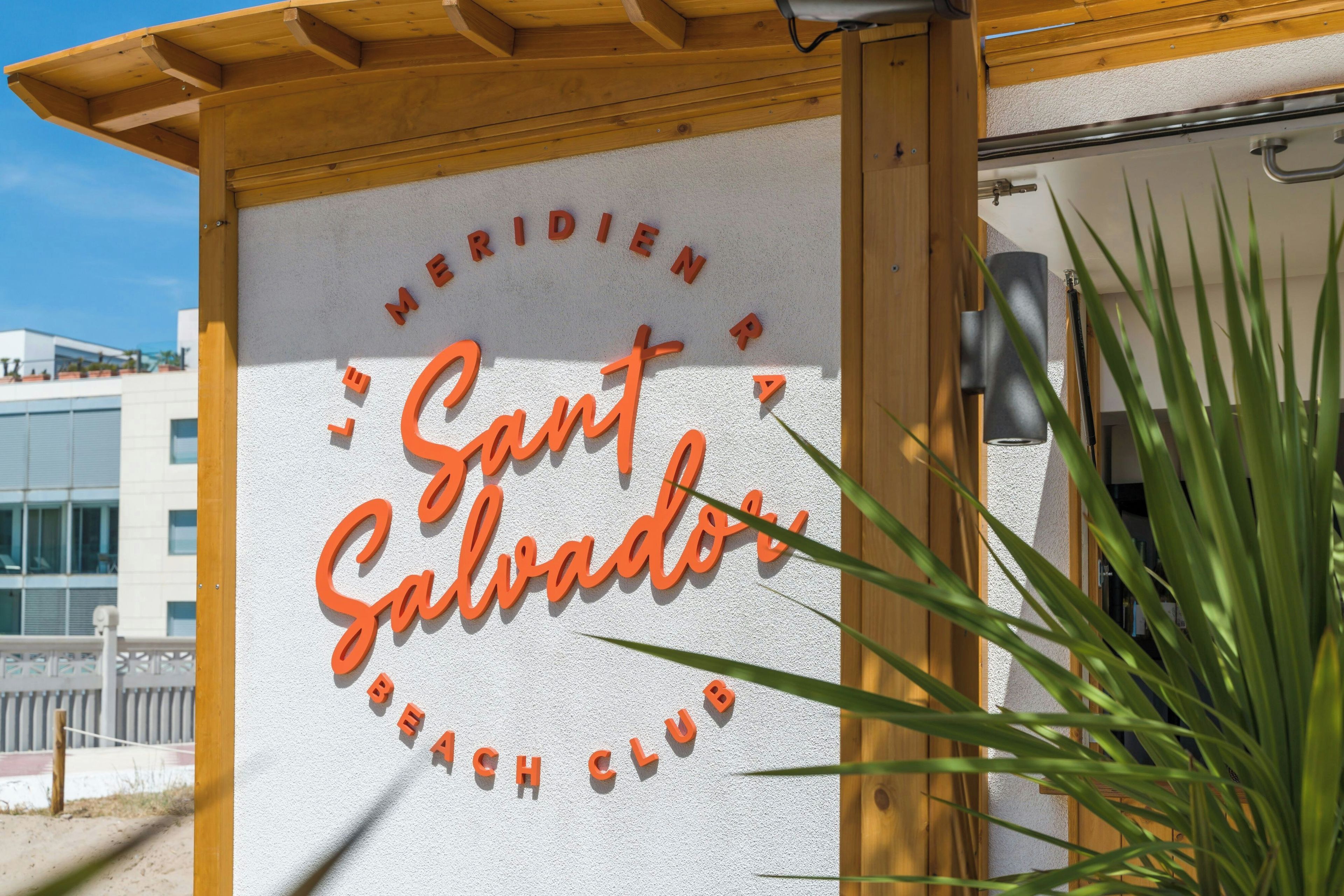 A sign for 'Meridian Beach Club' with the name 'Sant Salvador' in stylized lettering.
