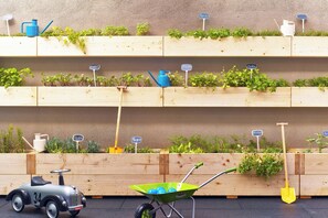 Una jardinera de madera con diversas plantas y herramientas de jardinería.