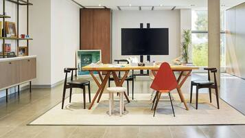 Un comedor moderno con una mesa grande, sillas y una pantalla de televisión.