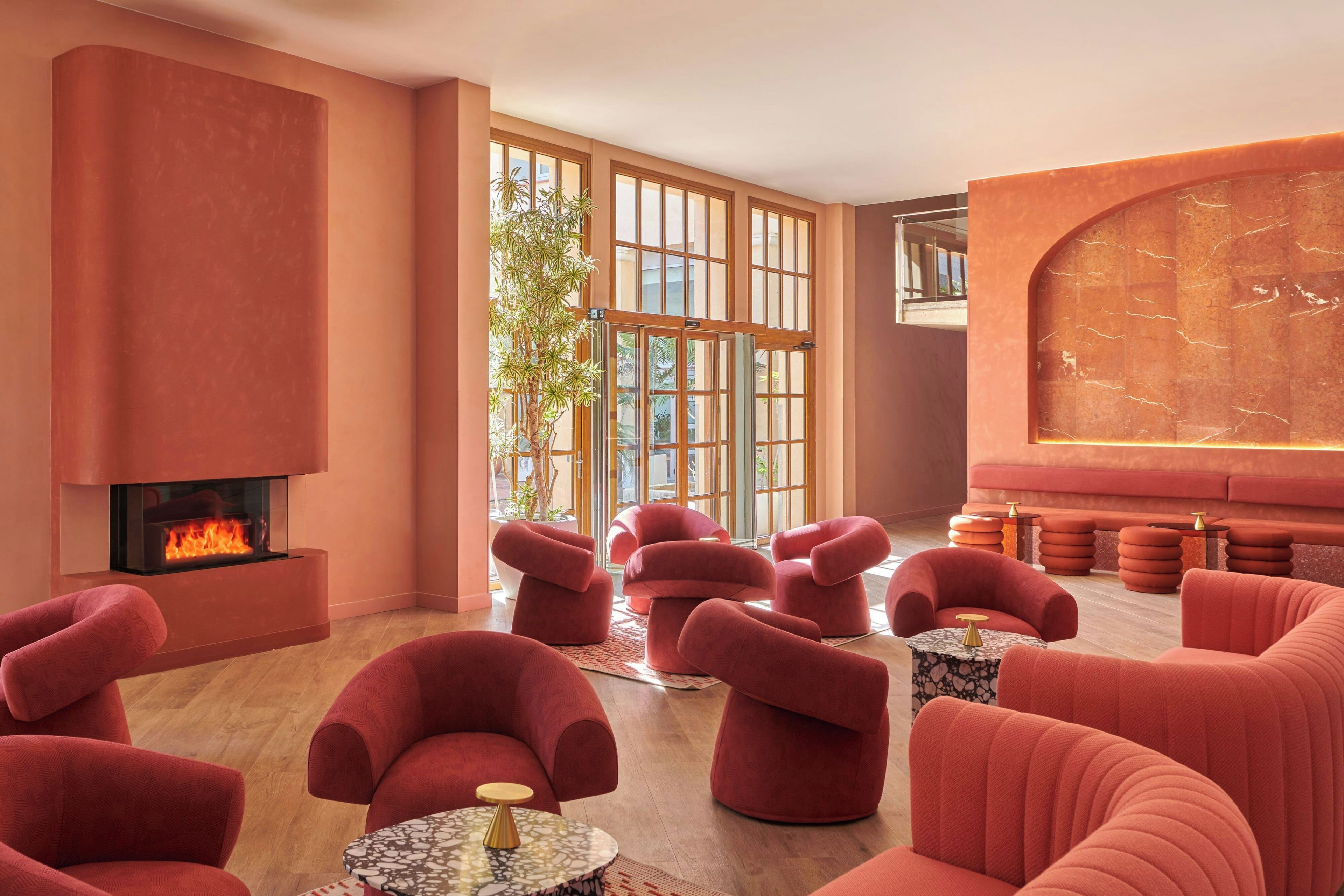 Ein moderner Lounge-Bereich mit Kamin, roten Polstersesseln und einer großen, gewölbten Wand.