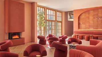 Ein moderner Lounge-Bereich mit Kamin, roten Polstersesseln und einer großen, gewölbten Wand.