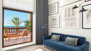 Una sala de estar con un sofá azul, una mesa de madera y vista al mar desde un balcón.