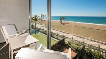 Een balkon met uitzicht op een strand, een zwembad en ligstoelen.