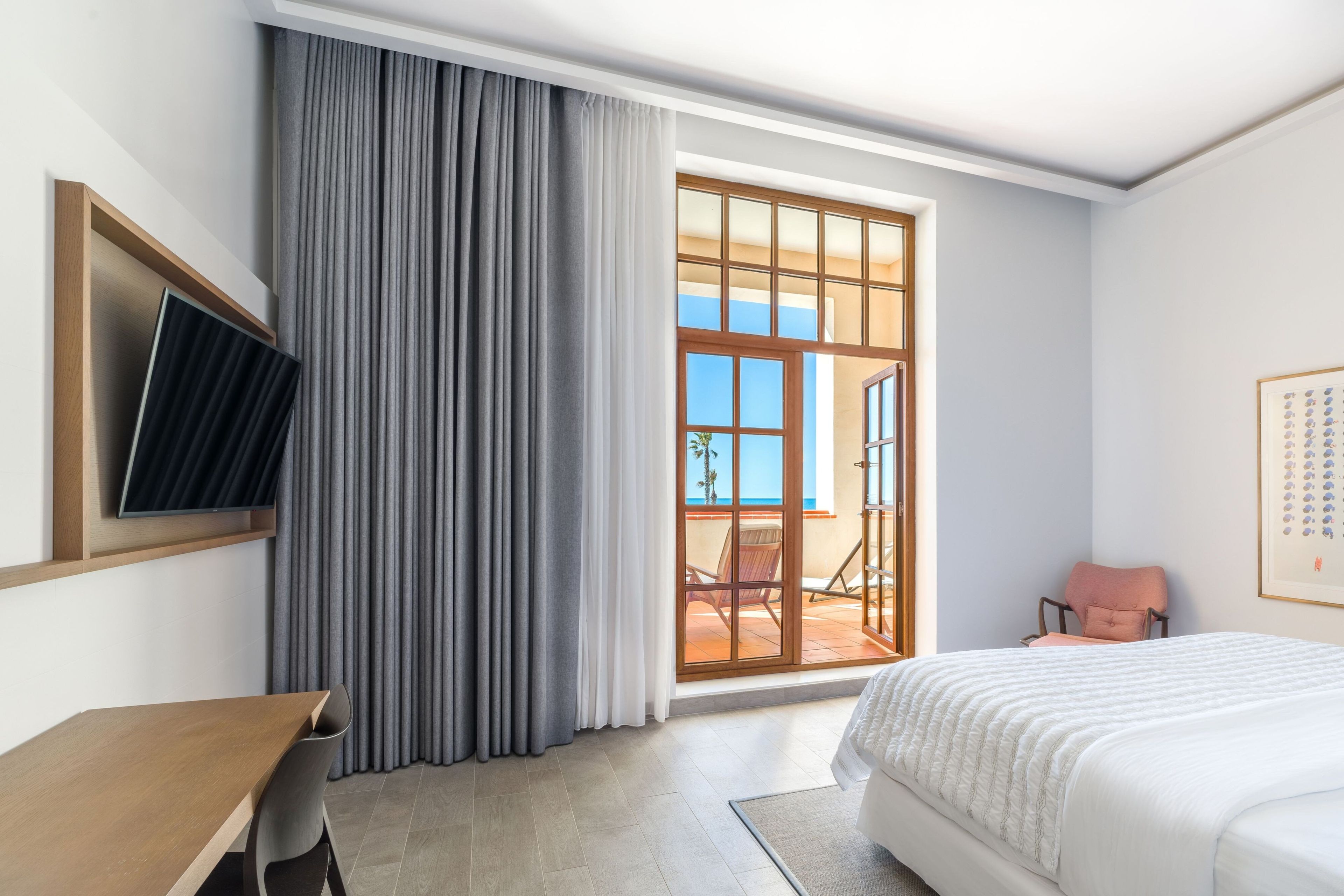 Een hotelkamer met een bed, een bureau, een stoel, een televisie en uitzicht.