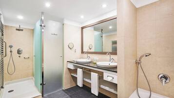 A modern bathroom with two sinks, a glass shower enclosure, and a bathtub.