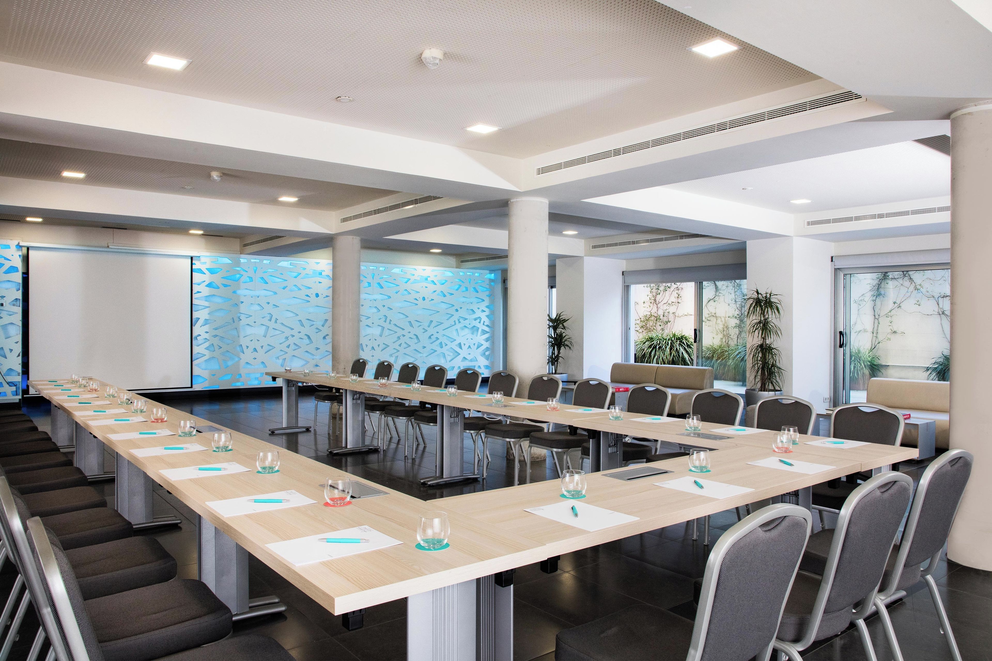 Una sala conferenze con un lungo tavolo, sedie e uno schermo per proiezioni.