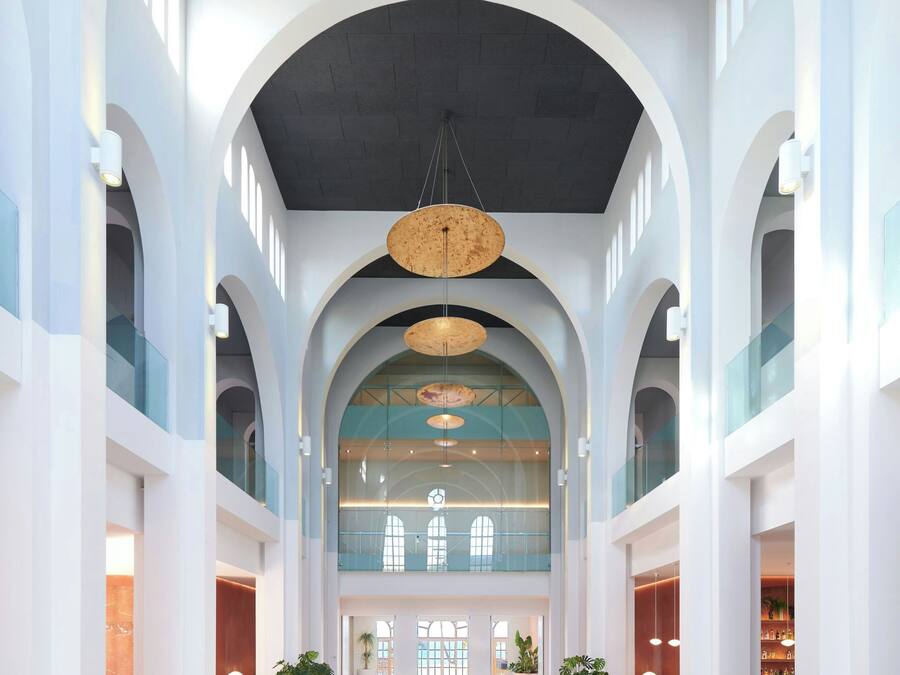 A spacious lobby with high ceilings, arched columns, and a central open area with a ceiling light fixture.