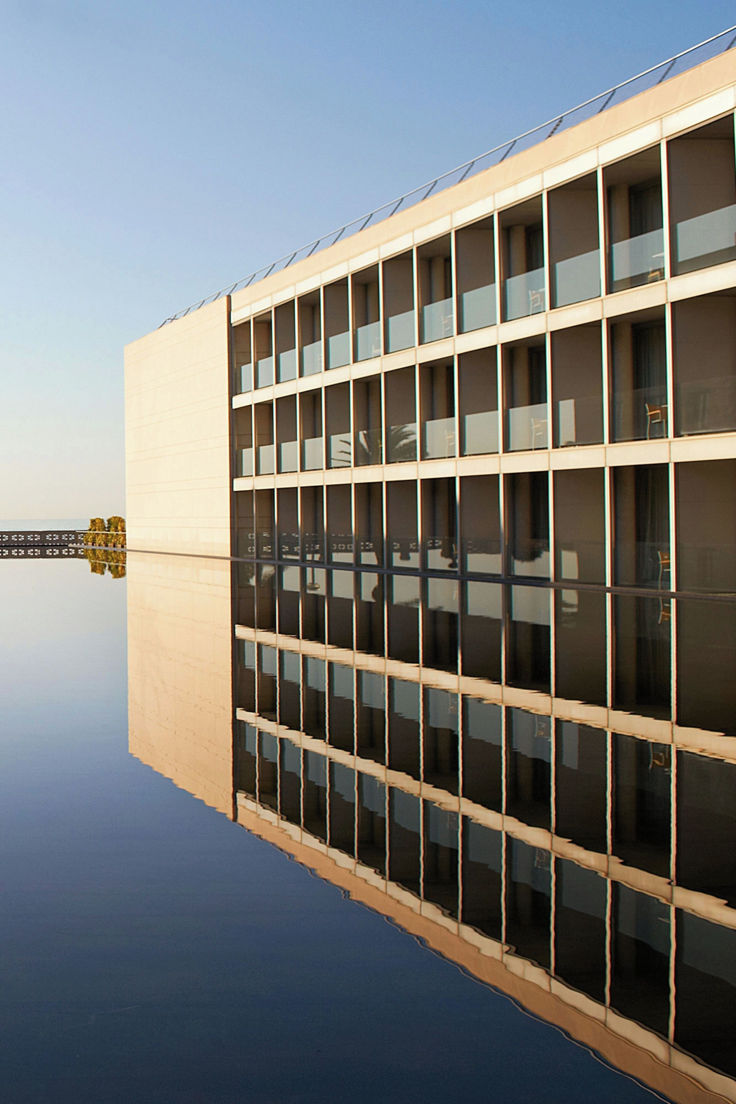 Un edificio moderno con fachada de vidrio reflectante, techo plano y diseño simétrico.