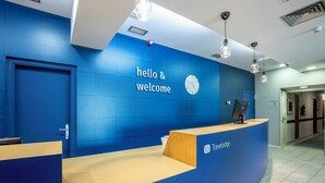 Un mostrador de recepción con una pared azul, un reloj y un cartel que dice 'hello & welcome'.