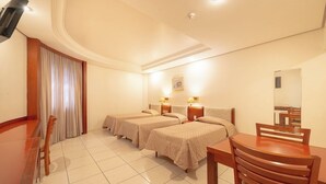 A hotel room with two beds, a dining table, and a mirror. - Real Castilha Hotel (São Paulo)