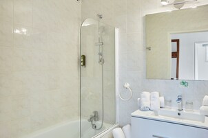 A bathroom with a glass-enclosed shower, a sink with two mirrors, and a white vanity.