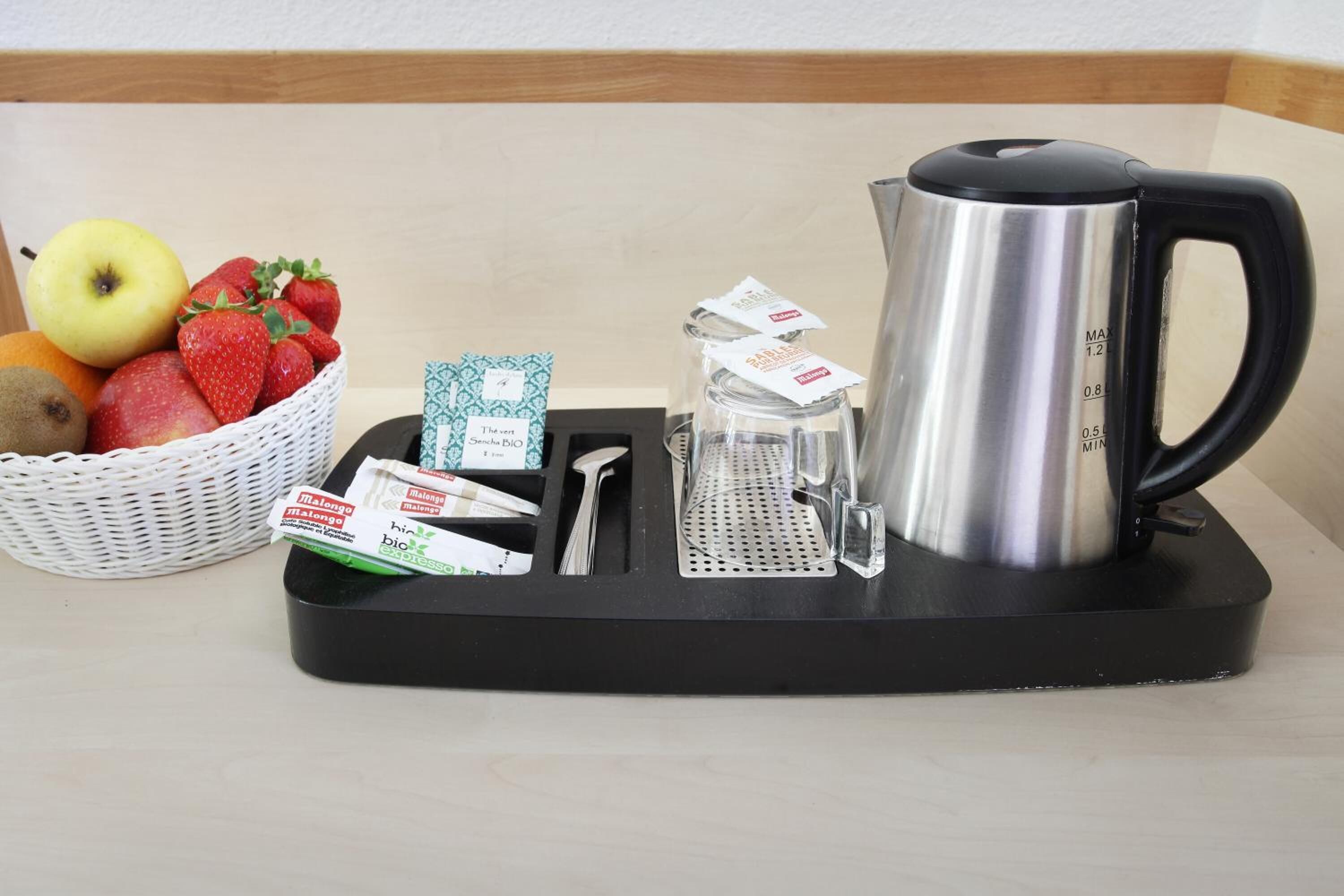 Una cocina equipada con una tetera, una cesta de fruta y algunas bolsitas de té.