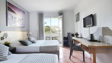 A hotel room with two beds, a desk, a chair, a TV, and a balcony with a view.