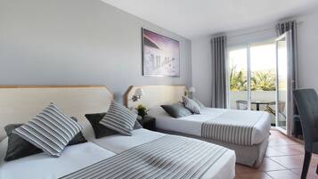 Une chambre d’hôtel avec deux lits, un tableau au mur, une fenêtre avec des rideaux et une vue sur des palmiers à l’extérieur.