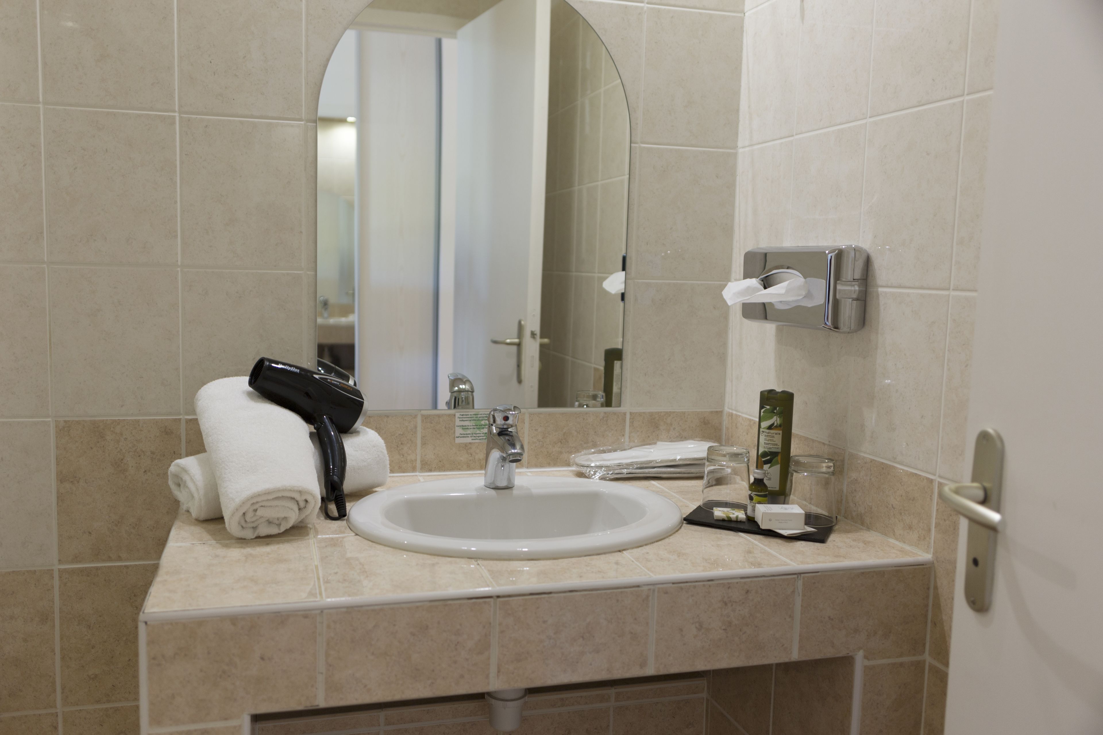 A bathroom with a sink, mirror, towel rack, and toiletries.