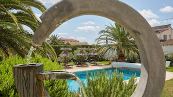 Una piscina al aire libre de temporada, sombrillas