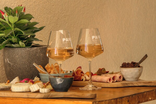 A table with two wine glasses, a bowl of chocolate, and various cheeses and meats.
