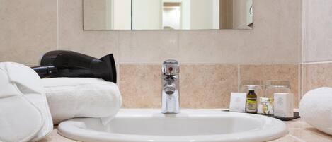 A bathroom with a sink, mirror, and toiletries.