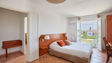 A bedroom with a bed, bedside tables, a bench, and a view of the outside.