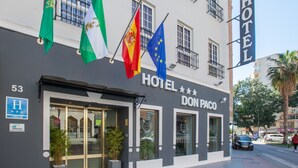 Un hotel llamado DON PACO con varias banderas, incluyendo la bandera de la UE, y un letrero que indica que es un HOTEL URBANO.