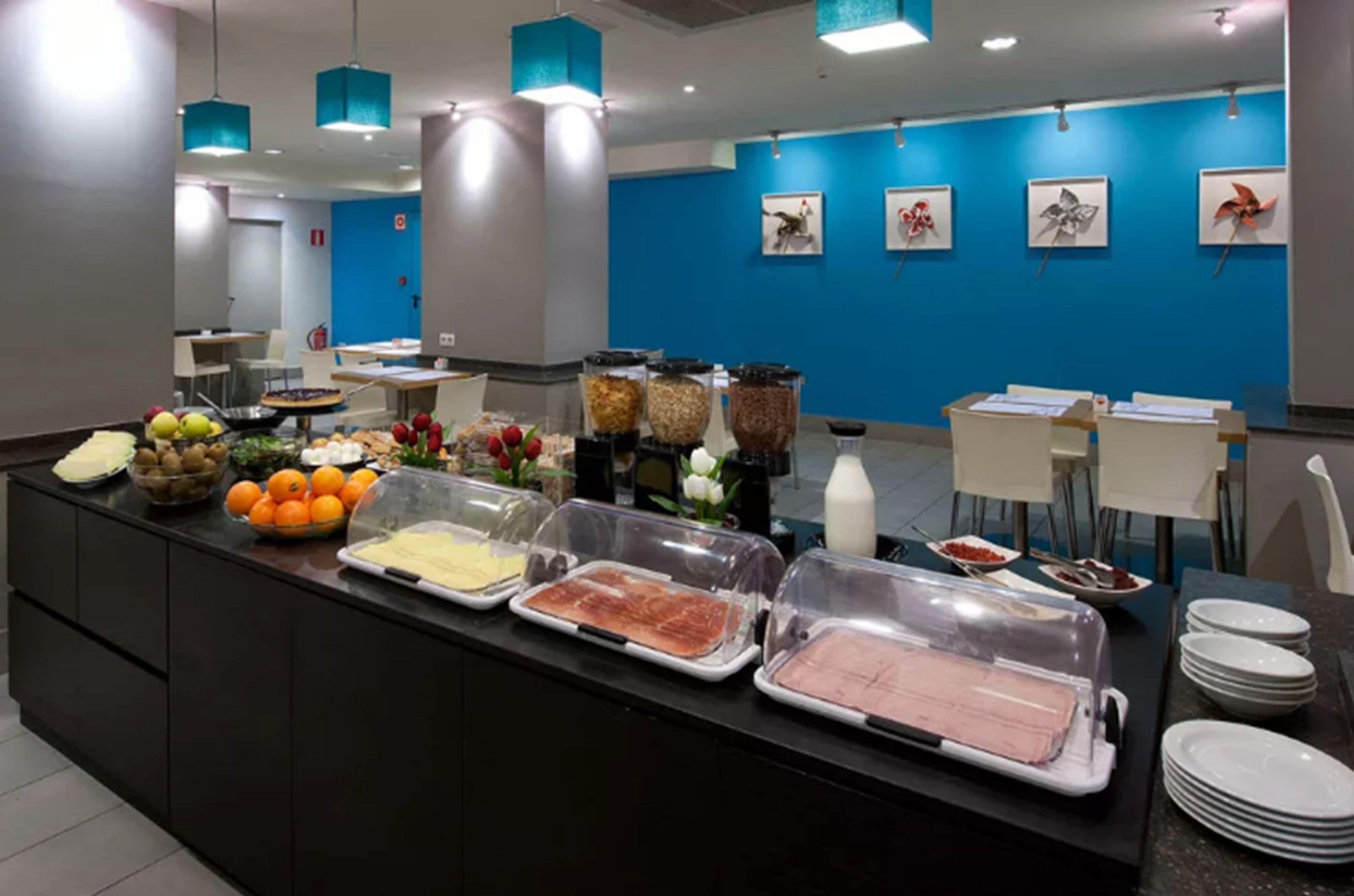 Zona de bufé con diferentes alimentos y una pared azul decorada con cuadros.