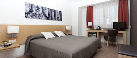 Une chambre d’hôtel avec un grand lit, un bureau avec un ordinateur, une chaise et un téléviseur.