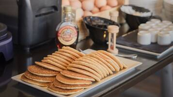 Un ricco buffet della colazione con pancake, uova e salse.