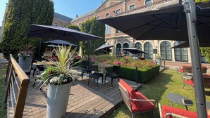 Eine Außenpatio-Terrasse mit Holzboden, Metallstühlen und -tischen unter großen Sonnenschirmen.