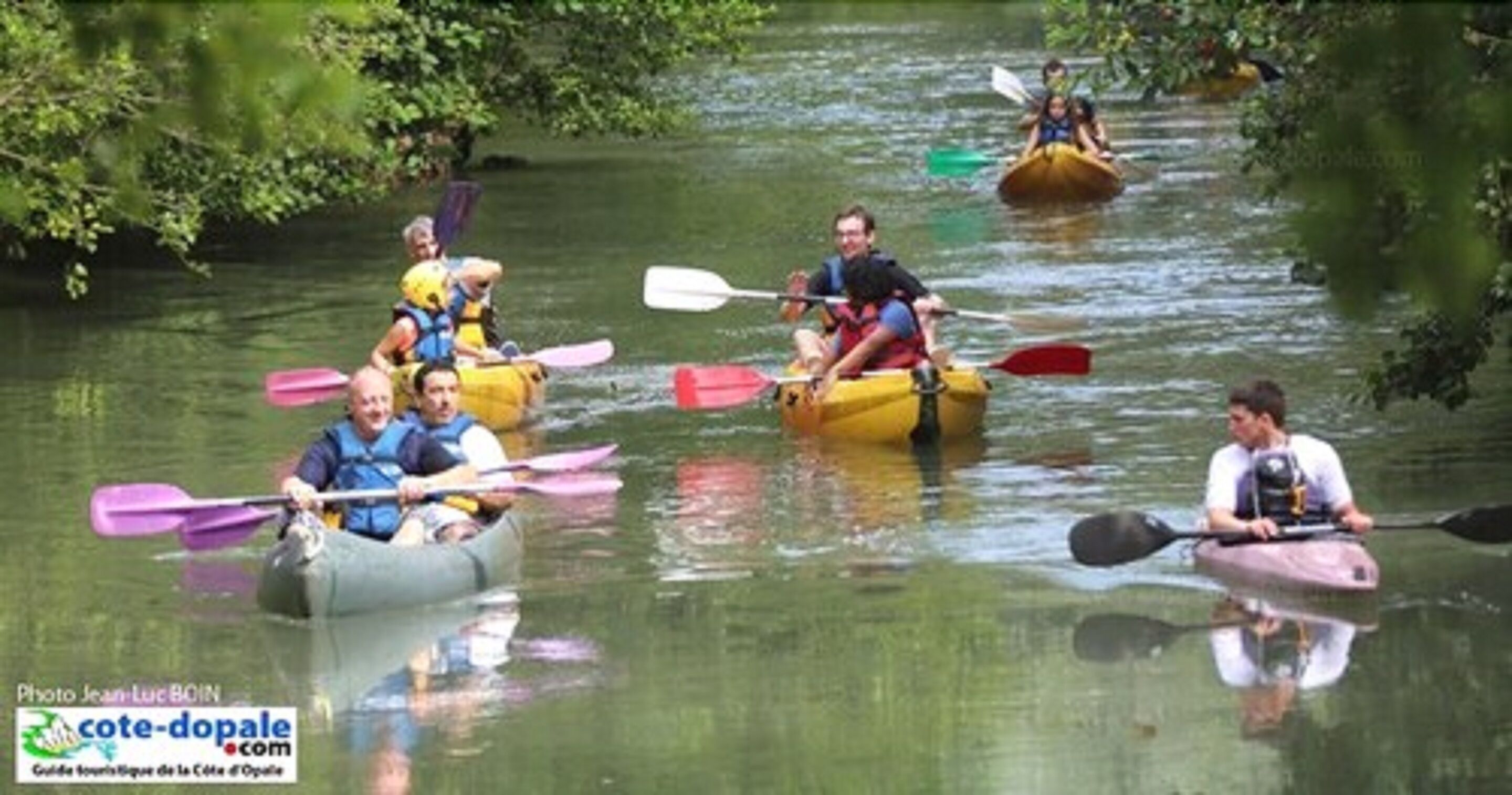 Des personnes pratiquent le kayak sur une rivière.