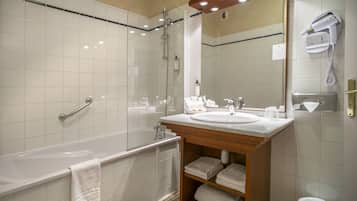 Une salle de bain moderne équipée d’une baignoire, d’un lavabo, d’un miroir et d’un sèche-cheveux.