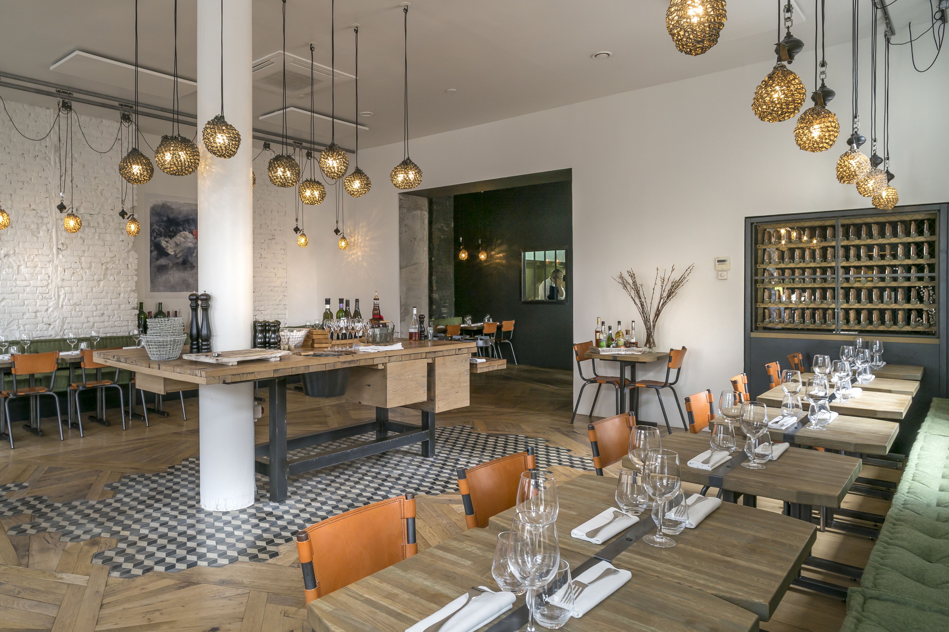 Un restaurant avec des tables en bois, des luminaires sphériques suspendus et un sol à motifs à carreaux.