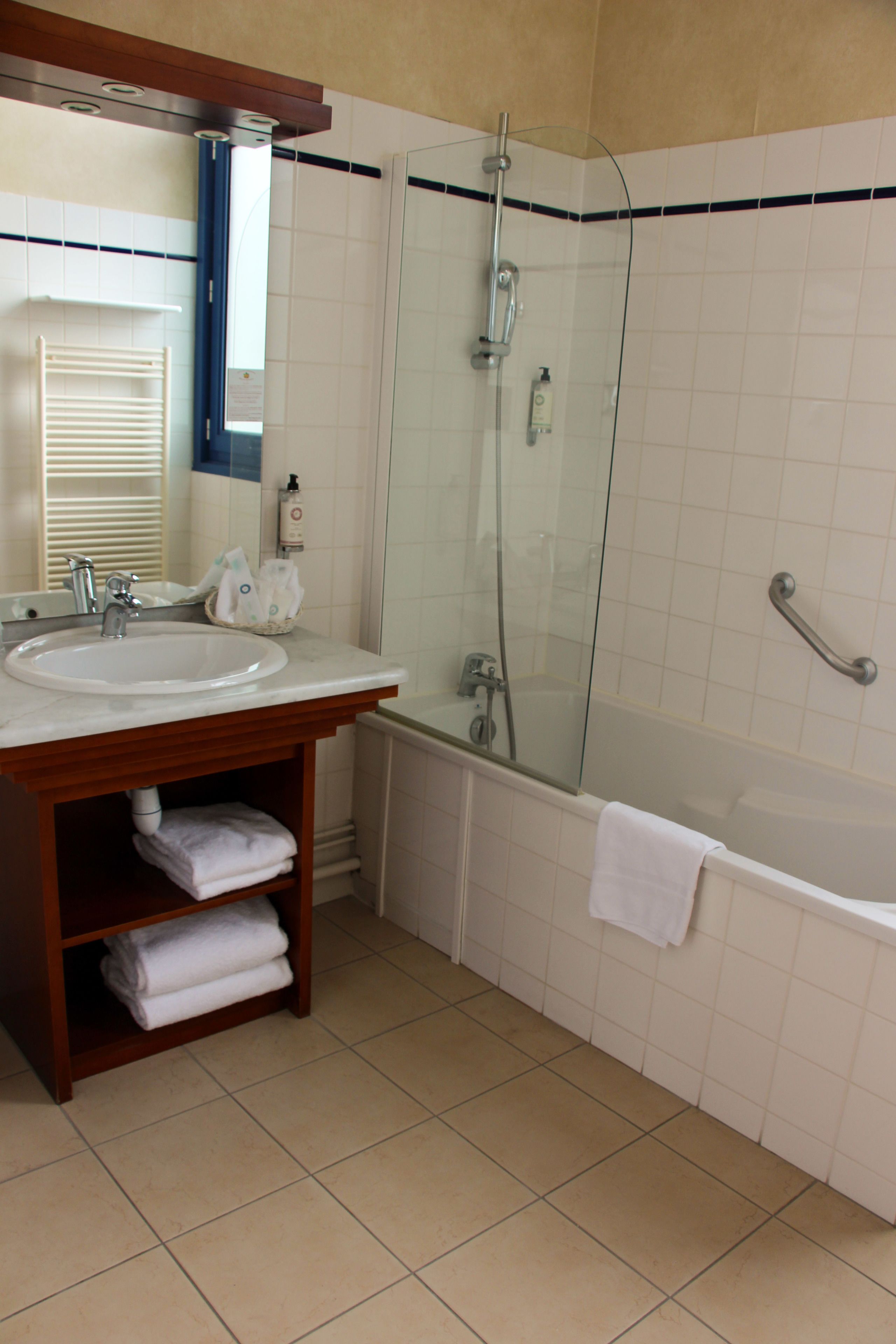 A bathroom with a sink, mirror, towel rack, and a glass-enclosed shower area.