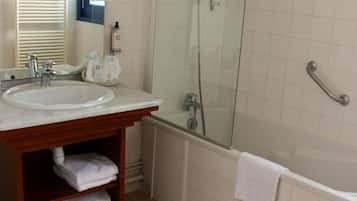 A bathroom with a sink, mirror, towel rack, and a glass-enclosed shower area.