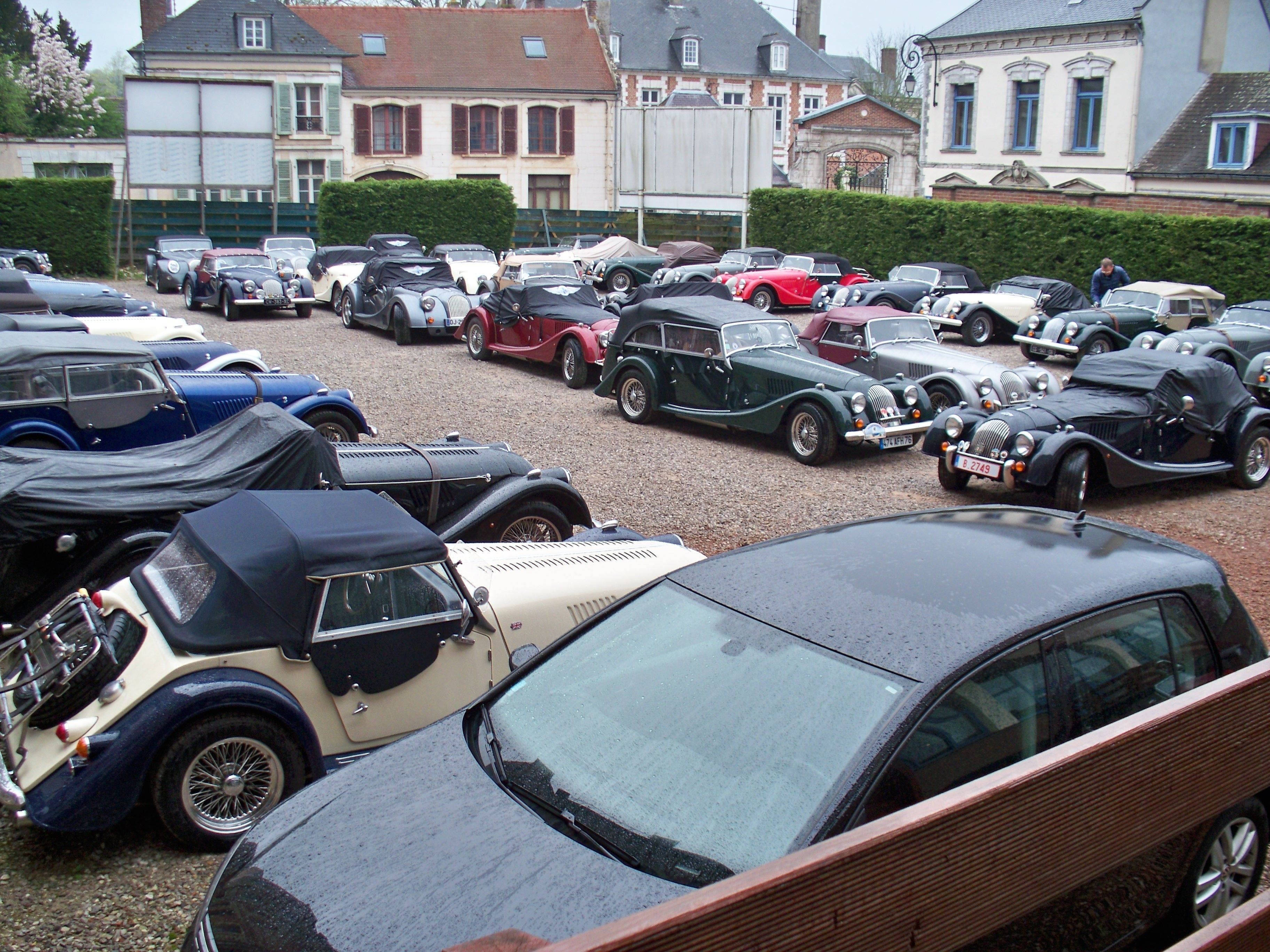 Ein Parkplatz voller alter Autos, umgeben von Wohnhäusern.