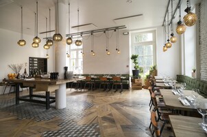 Un restaurante con una larga mesa de madera, múltiples lámparas esféricas colgantes y un suelo con diseño.