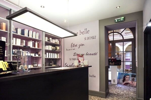 A modern boutique hotel lobby with a reception desk, shelves with toiletries, and a wall with motivational quotes.