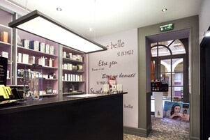 Un lobby moderno de hotel boutique con una recepción, estantes con artículos de aseo y una pared con citas motivacionales.