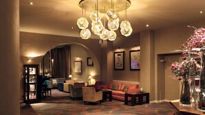 Eine Hotellobby mit einem gemusterten Teppich, einem roten Sofa, einem Couchtisch und einer dekorativen Vase mit Blumen.