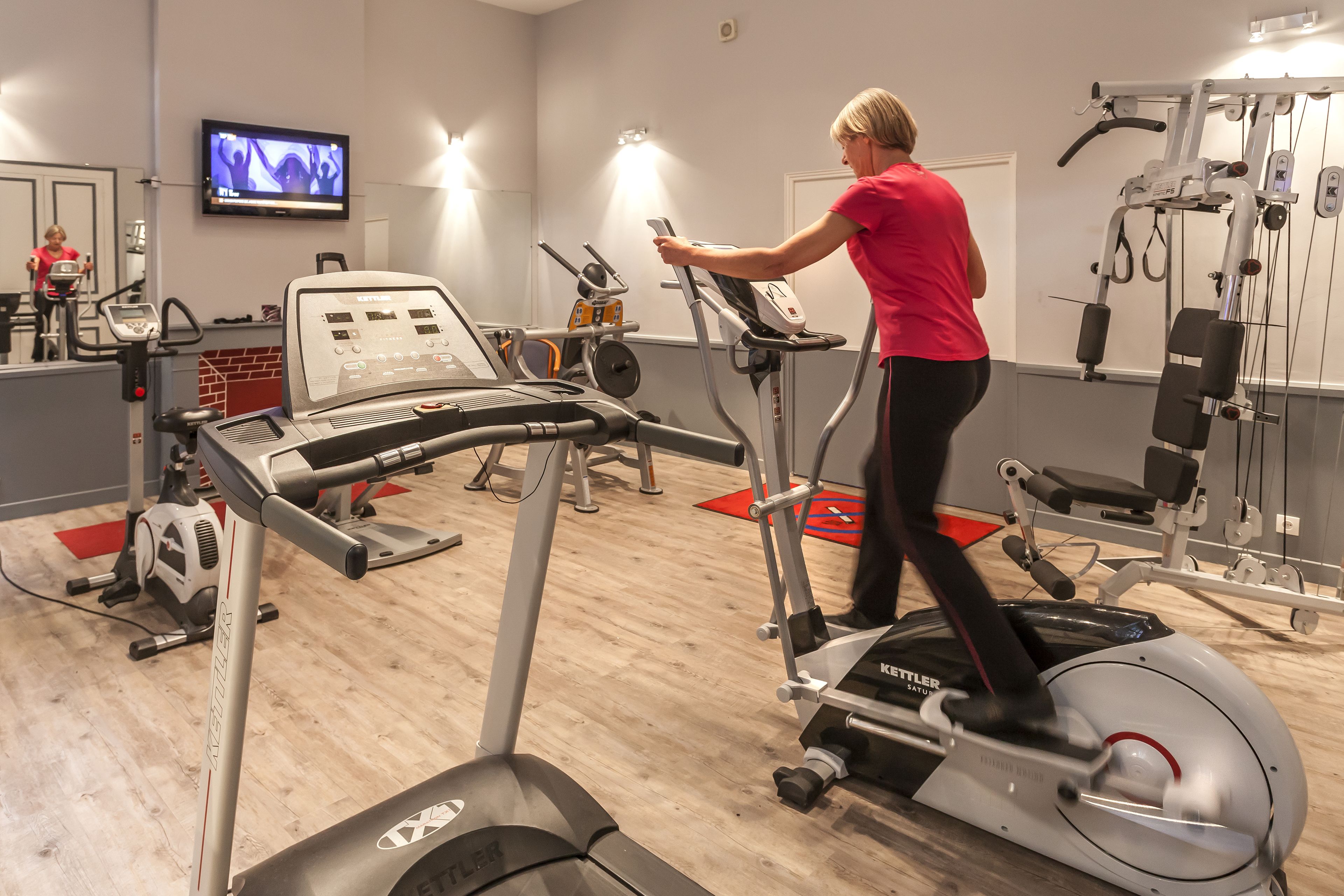 A gym with cardio machines, a television, and various exercise equipment.