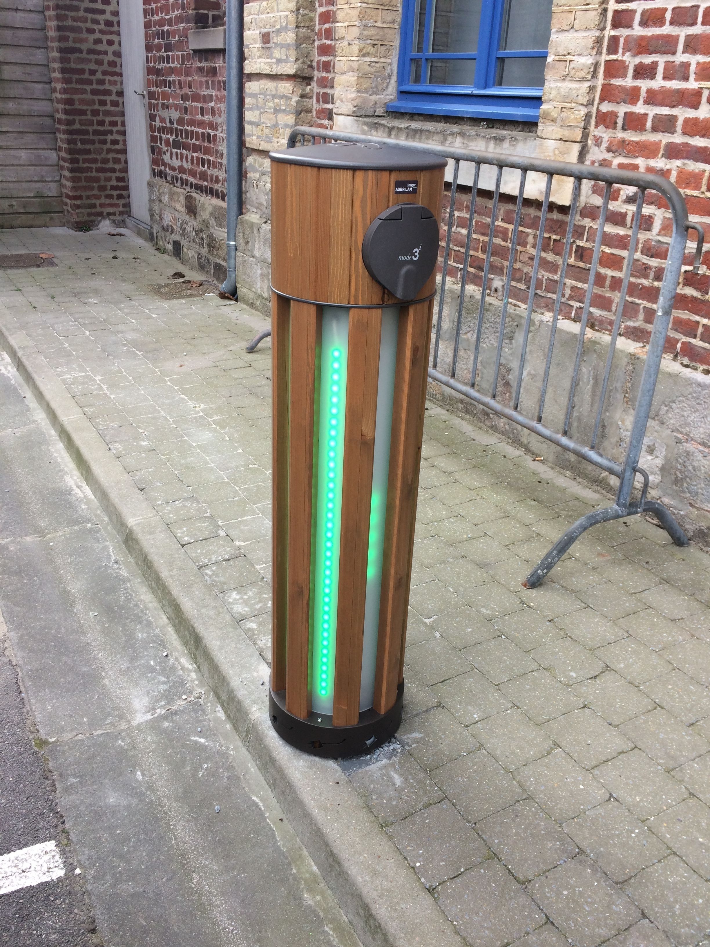Un objet cylindrique doté d’une enveloppe extérieure en bois et d’un sommet noir, agrémenté d’une bande lumineuse à LED verte et d’un panneau de commande.