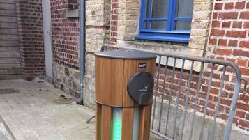 Un objet cylindrique doté d’une enveloppe extérieure en bois et d’un sommet noir, agrémenté d’une bande lumineuse à LED verte et d’un panneau de commande.