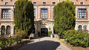 Ein historisches Gebäude mit einer symmetrischen Fassade, großen Fenstern und einem zentralen Eingang mit einem dekorativen Bogen.