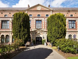 Un edificio histórico con fachada simétrica, ventanas amplias y una entrada central con arco decorativo.